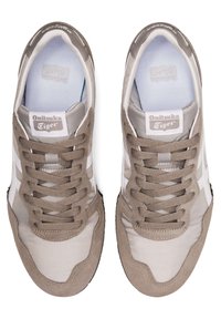 Béžové a světle šedé tenisky s svrchní částí z semiše a textilu, plochými tkaničkami, bílými pruhy, gumovou podrážkou a logem značky na jazyku.