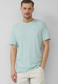 Jasno niebieski t-shirt z krótkim rękawem wykonany z miękkiego materiału; okrągły dekolt z małym logo w lewym górnym rogu. Luźny krój.