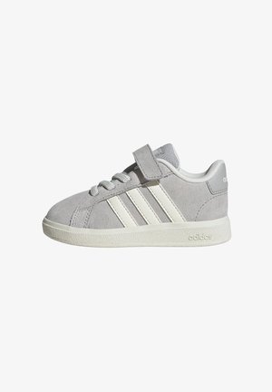 Sivá Adidas semišová teniska s bielymi pruhmi, bielou podrážkou, šnúrkami a jedným suchým zipsom na vrchu.