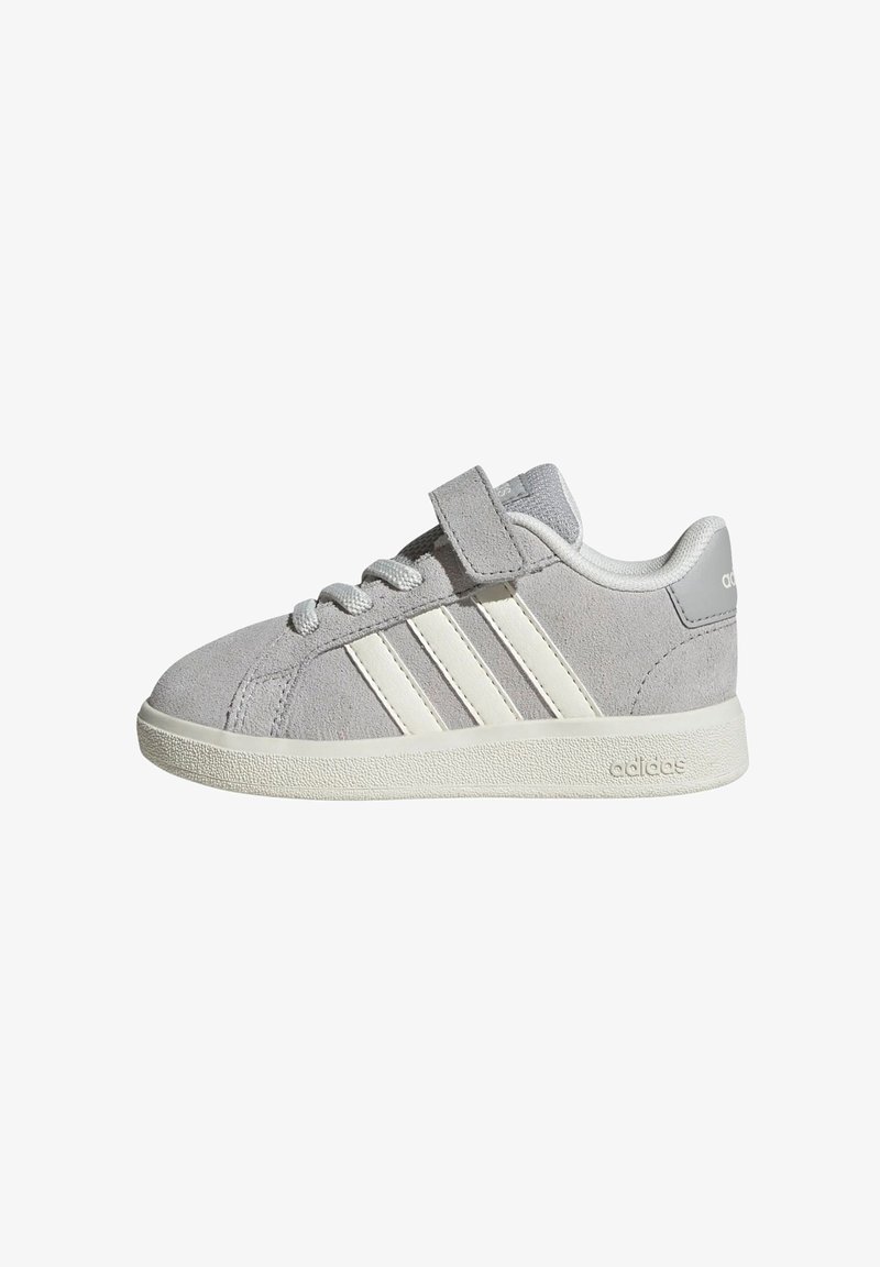 Baskets Adidas en daim gris avec des bandes blanches, une semelle blanche, des lacets et une seule bride Velcro sur le dessus.