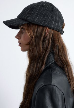 Gray wool cap with pinstripes, curved brim, and a rear adjustable strap, worn with a black leather jacket. Profile view.