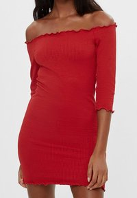 Červené šaty s odhalenými rameny, 3/4 rukávy, žebrovaná textura, volánkové lemy u výstřihu a rukávů, přiléhavý střih, délka nad kolena.