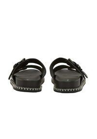 Schwarze Sandalen mit strukturiertem Obermaterial, ausgestattet mit verstellbaren Riemen und einer dicken Sohle, die am Rand mit weißem Stich versehen ist.