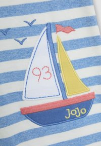 Pruhovaná tkanina má modro-bílý vzor; vyšívaná plachetnice s modrými, žlutými a červenými akcenty; zahrnuje číslo "93" a jméno "Jojo."
