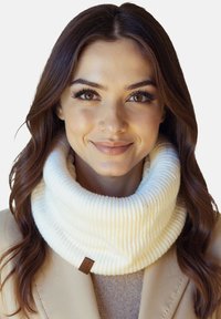 Hvid ribstrikket halsedisse med blød tekstur, der har et lille brunt mærke; båret over en beige sweater og frakke.