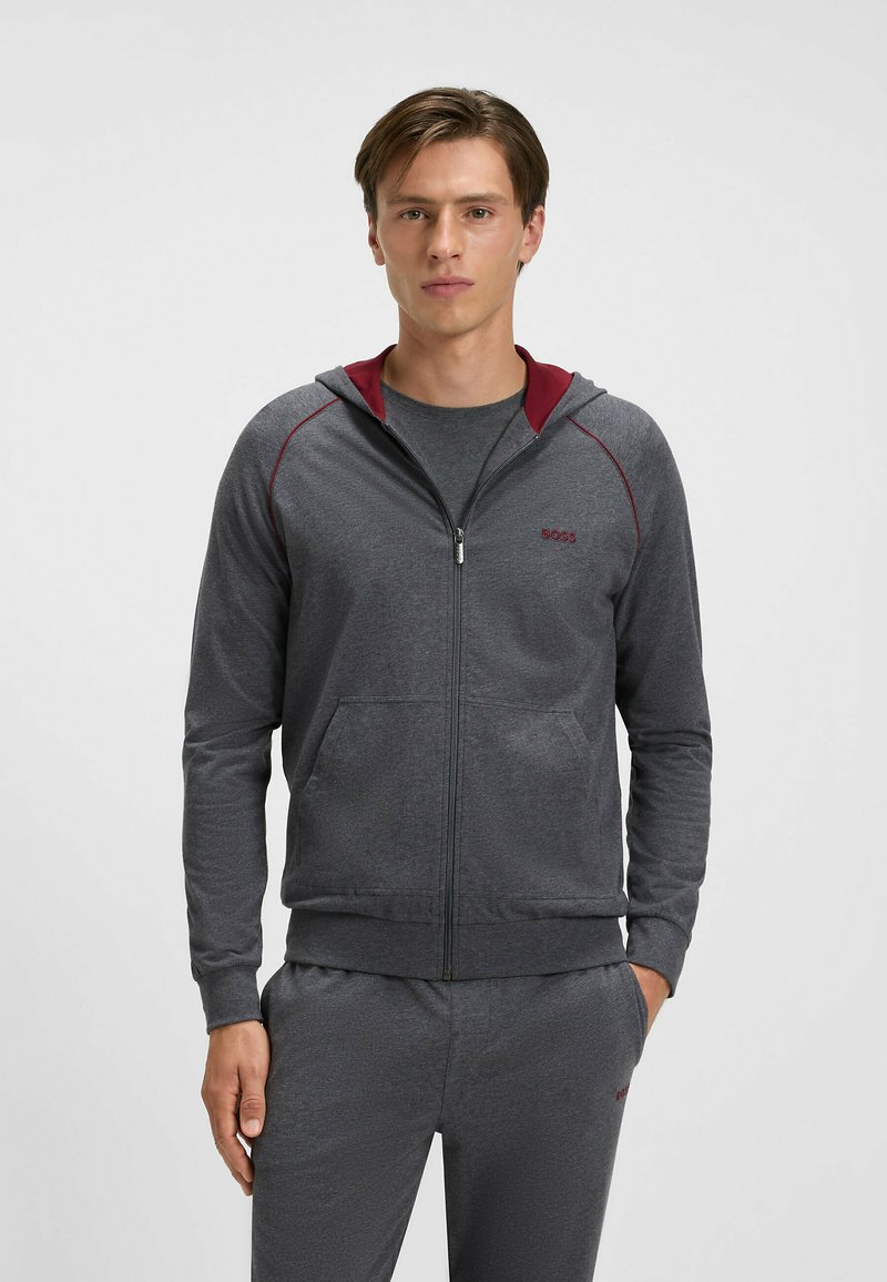 Gray zip-up hoodie with a contrasting maroon hood lining, long sleeves, front pockets, and stitched detailing along the shoulders.