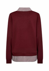 Burgundziwy sweatshirt z paskowanym kołnierzykiem na dole. Długie rękawy z ściągaczami i gładką fakturą materiału.