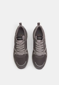 Gray athletic shoes featuring a mix of smooth and textured materials, with lace-up design, reflective accents, and a pull tab on the heel.