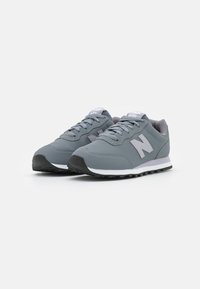 Scarpe da ginnastica grigie con tomaia in sintetico liscio, colletto imbottito, design con lacci, suola intermedia bianca a contrasto e suola nera testurizzata.
