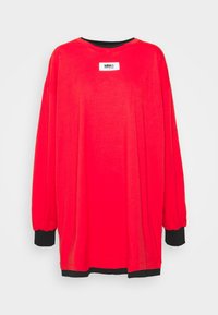 Långärmad röd oversized skjorta med svarta manschetter och fåll, med en vit "MM6 Maison Margiela" logopatch på bröstet.