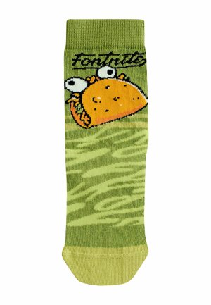 Zaļās zeķes ar takoa grafiku, kurai ir baltas acis un oranžas detaļas. Modelēts raksts ir izkliedēts visā audumā.