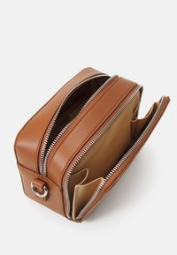 Borsa in pelle marrone con due scomparti con zip, forma rettangolare e cerniere in tonalità argento. L'interno è caratterizzato da una fodera beige e tasche per carte.