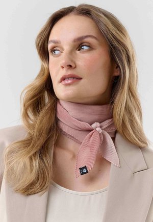Woman wearing a light pink ribbed scarf tied around her neck, beige blazer, and light top, looking slightly to the side.