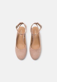 Pink suede slingback shoes with a round toe, ankle strap, and a smooth inner sole, featuring a subtle logo on the insole.