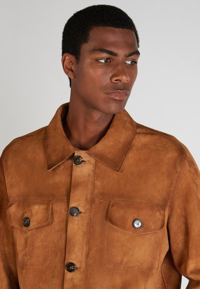 Braune Wildlederjacke mit Kragen, vorderem Knopfverschluss und zwei Brusttaschen. Verfügt über dunkle Knöpfe und eine glatte, strukturierte Oberfläche.