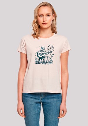 Light pink cotton t-shirt featuring a graphic of a skeleton playing guitar, surrounded by musical notes and hearts. Simple, casual design.