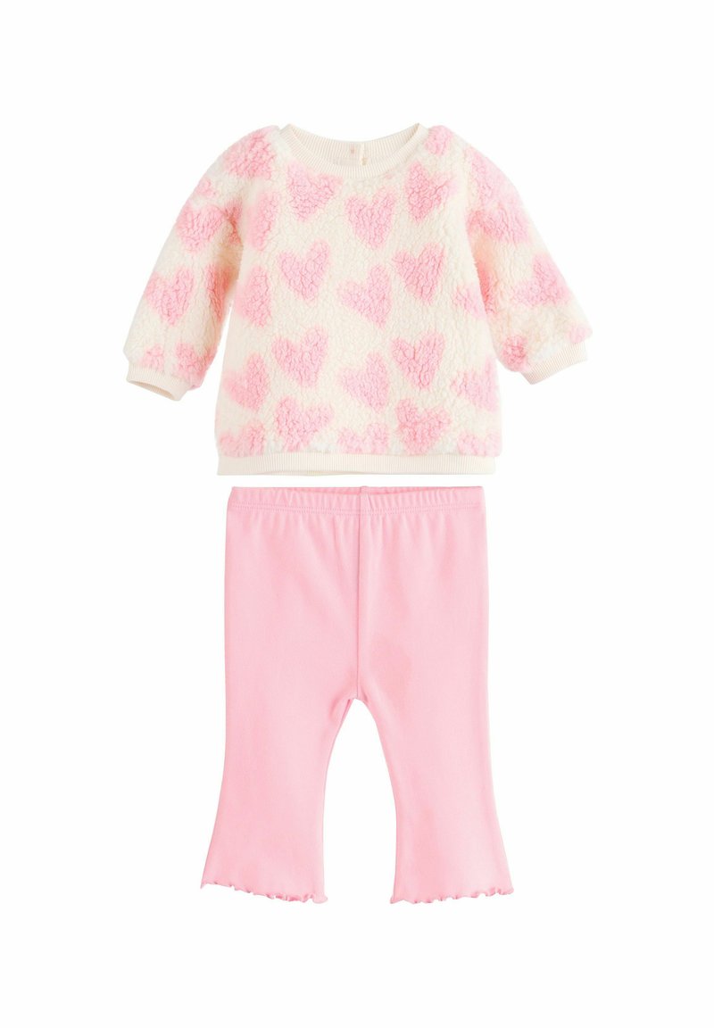 Fehér alapon rózsaszín szívmintás polár pulóver, hosszú ujjal; rózsaszín leggings-szel párosítva, fodros szegéllyel. Puha, texturált anyag.