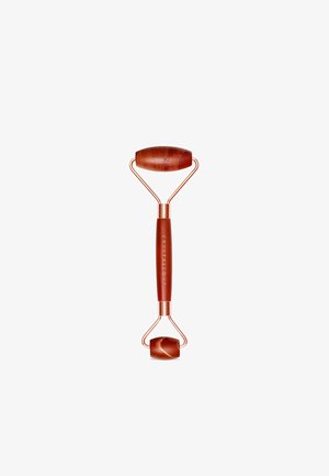 Czerwony jadeitowy wałek do twarzy z solidną, różowo-złotą metalową ramą. Posiada dwa kamienie do rollowania: jeden większy i owalny, drugi mniejszy i okrągły.