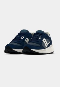 Tamsiai mėlyni sportbačiai iš subtilaus zomšos ir tinklelio medžiagų derinio, su baltu viduriu, pilkais akcentais ir guminio pado su sukibimu.