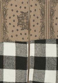 Tessuto marrone con un motivo paisley, unito a un tessuto a scacchi bianco e nero. Presenta una chiusura centrale con zip.