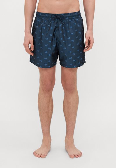 Pantaloni da bagno blu navy con un motivo sottile di forme triangolari blu, vita elastica con cordoncino e una texture leggera e liscia.