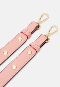 Rosa texturerad rem med guldhardware, som har två klipp, sömmar och dekorativa nitar. Tvåtonig design med en blank yta.