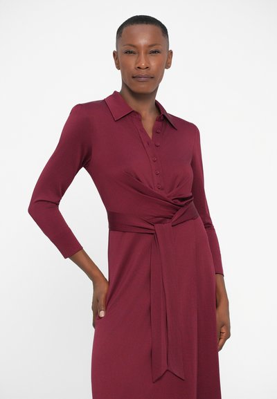 Maroon mekko, jossa on napitettu etuosa, pitkät hihat ja solmittava vyötärö. Valmistettu sileästä kankaasta, jossa on hienovarainen rakenne.