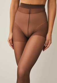 Pruunid kõrge vöökohaga sukkpüksid, millel on läbipaistev ülemine osa, tekstuuriga viimistlus ja sile alumine sääreosa, esiküljel peene õmblusega.