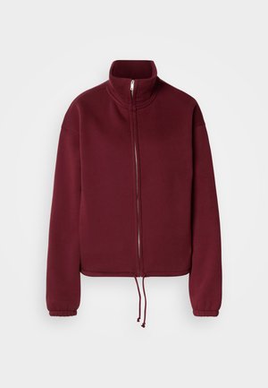 Vinrød genser med glidelås, høy krage, lange ermer og snor i kanten. Har glatt tekstur og elastiske mansjetter.