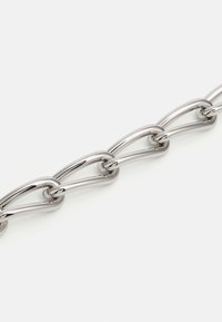 Sølvfarvet metal kæde med forlængede, ovale led med en glat, blank overflade. Designet er ensartet med en let glansfinish.
