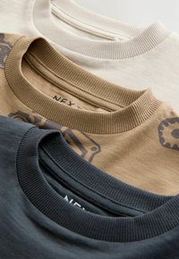 Tre crew-neck t-shirts i beige, khaki med grafik og mørk navy. Blødt bomuldsstof med ribbede kraver og subtile teksturer.