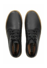 Chaussures en cuir noir avec un bout arrondi, équipées de lacets noirs, d'une semelle intérieure rembourrée marron et d'une semelle en caoutchouc marron texturée.