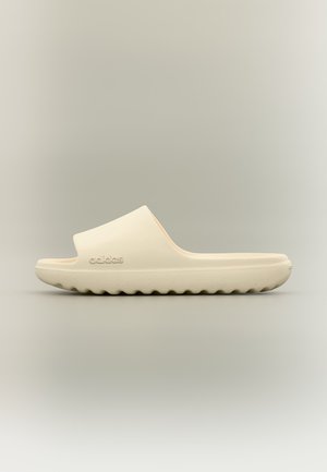 Μπεζ σανδάλι Adidas slide με παχιά σόλα και ραβδώσεις στην κάτω πλευρά, με το λογότυπο Adidas στο πλάι.