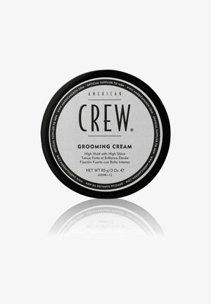 Ronde zwarte en zilveren container van American Crew Grooming Cream, gelabeld voor hoge hold en hoge glans, 85g/3oz gewicht.