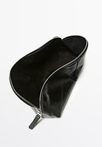 Sort læderpung med en glat yderside og blødt tekstilindvendigt. Har en sølvfarvet lynlås og en åben top for nem adgang.