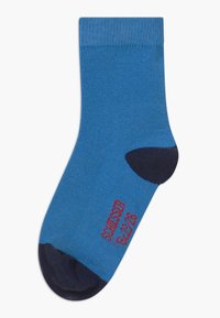 Chaussettes bleues en mélange de coton, avec des sections de talon et de orteil bleu marine. Un texte rouge sur le côté indique "SWEATER GOOSE." Longueur mi-mollet.