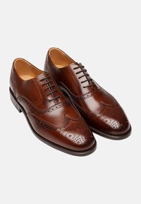 Scarpe eleganti in pelle marrone con dettagli perforati, design a punta d'ala e punta arrotondata. Presentano un'allacciatura frontale e una finitura liscia.