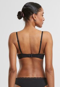 Soutien-gorge en satin noir avec des bretelles ajustables et une fermeture à crochet. Texture lisse avec un minimum de détails. Coupe classique et design simple.