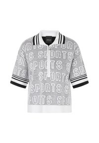 Haut tricoté blanc à manches courtes avec col et poignets rayés noirs, fermeture éclair à l'avant et motif de texte perforé répété "SPORTS".