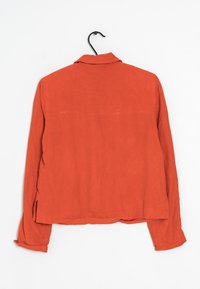 Rustinvärinen, långärmad skjorta med krage, som har en mjuk yta och sidoflikar vid fållen för ökad rörlighet.