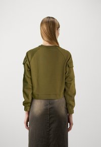 Sweat-shirt court vert olive à encolure ronde, manches raglan et poignets élastiques. Le tissu semble doux avec une texture lisse.