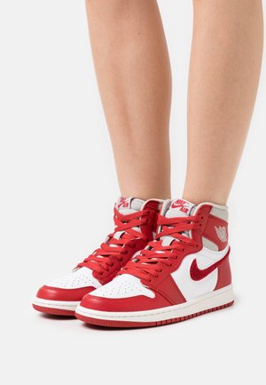 Zapatillas altas de cuero en rojo y blanco, con puntera perforada, cordones rojos y el logotipo de Nike Air en la lengüeta y el costado.