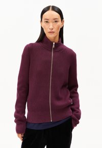 Paarse ribgebreide zip-up trui met een hoge kraag en een zilveren rits. Het kledingstuk heeft lange mouwen en een aansluitende onderrand.