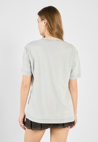 Light grey cotton t-shirt with short sleeves, relaxed fit, and a round neckline, paired with a black denim mini skirt with frayed hem.