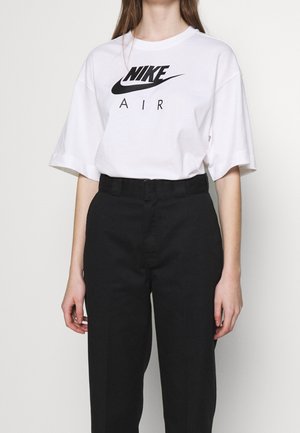 T-shirt en coton blanc avec logo "Nike Air" noir, coupe décontractée, manches courtes, associé à un pantalon noir taille haute. Design simple et tissu confortable.