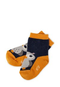 Marineblaue und orange Babystrümpfe mit einem Puffin-Vogelmotiv, wobei ein Socken teilweise den anderen überlappt, auf einem weißen Hintergrund.
