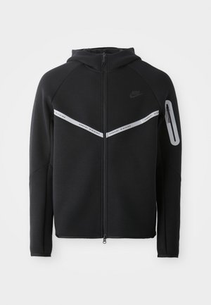 Sort zip-up hættetrøje med en reflekterende streg på brystet, justerbar hætte og en sidelomme med lynlåslukning.