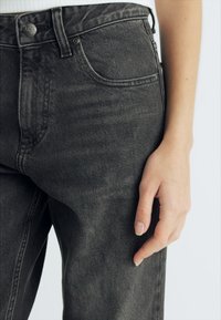 Zwarte denim jeans met een licht vervaagde afwerking, voorzien van een knoopsluiting, zijzakken en een slim-fit pasvorm.