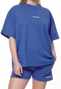 Blaues Baumwoll-T-Shirt und Shorts-Set mit lockerer Passform. Enthält ein kleines weißes "PEGADOR"-Logo auf dem Shirt, glatte Textur und kurze Ärmel.