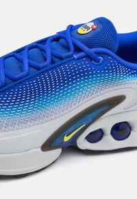 Baskets Nike Air Max bleues avec tige en maille, coutures détaillées, swoosh jaune sur la semelle intermédiaire et coussins d'air visibles.